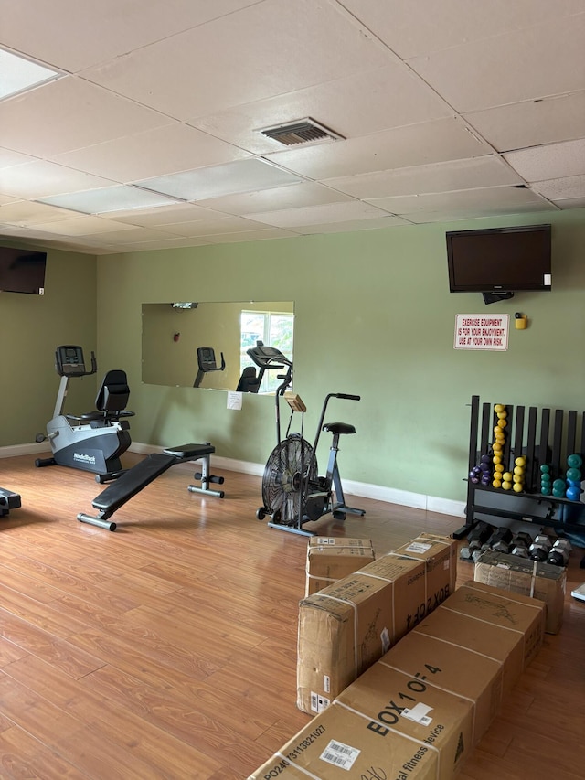 gym featuring baseboards, a drop ceiling, visible vents, and light wood-style floors