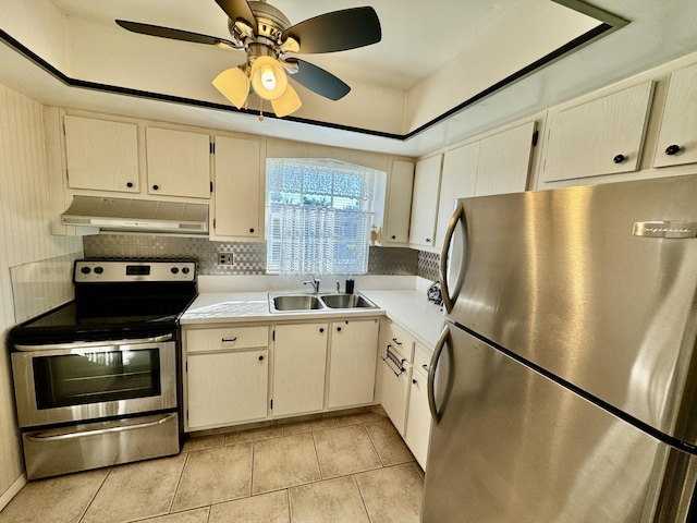 kitchen with ceiling fan, sink, a raised ceiling, light tile patterned floors, and appliances with stainless steel finishes