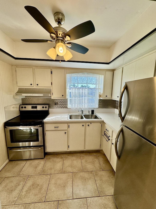 kitchen with light tile patterned floors, under cabinet range hood, stainless steel appliances, a sink, and light countertops