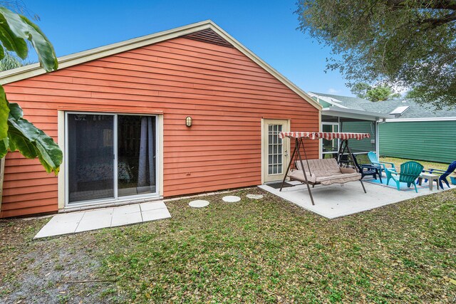 rear view of property featuring a patio and a lawn