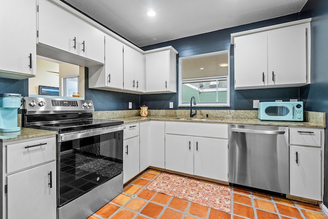 kitchen featuring sink, stainless steel appliances, white cabinetry, and light tile patterned flooring