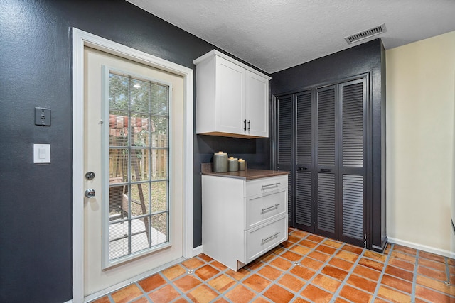 kitchen featuring a textured ceiling, light tile patterned flooring, and white cabinetry