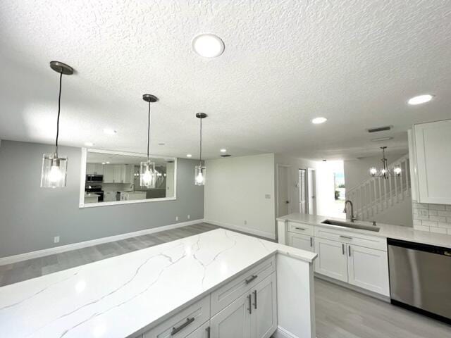 kitchen with dishwasher, white cabinets, decorative light fixtures, and sink