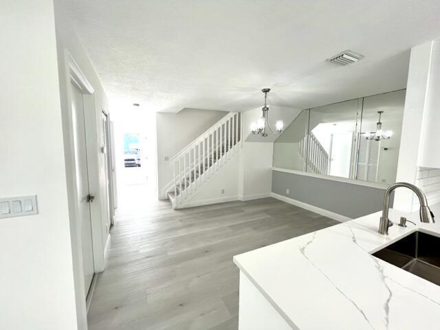 kitchen featuring white cabinetry, light wood-type flooring, light stone countertops, and sink