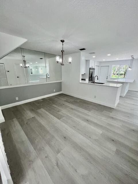 unfurnished living room featuring sink and light hardwood / wood-style floors