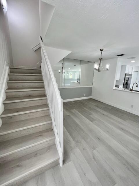 stairway with hardwood / wood-style flooring, sink, and a chandelier