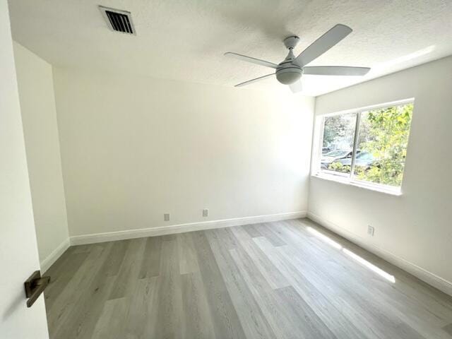 spare room with a textured ceiling, light hardwood / wood-style floors, and ceiling fan