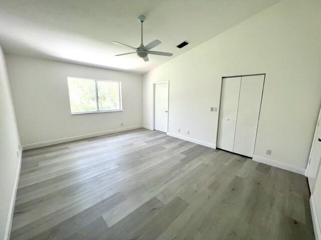 unfurnished bedroom featuring ceiling fan, light hardwood / wood-style floors, and vaulted ceiling