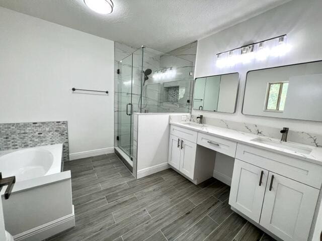 bathroom with vanity, independent shower and bath, and a textured ceiling