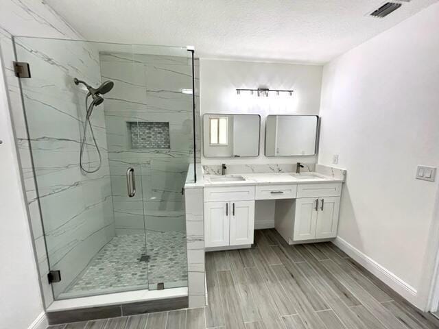 bathroom featuring vanity, a shower with shower door, and a textured ceiling