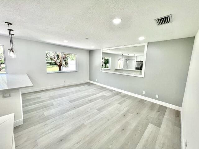 interior space with a textured ceiling, light wood-type flooring, and refrigerator