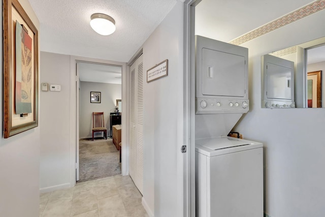 washroom with light tile patterned floors, a textured ceiling, and stacked washing maching and dryer