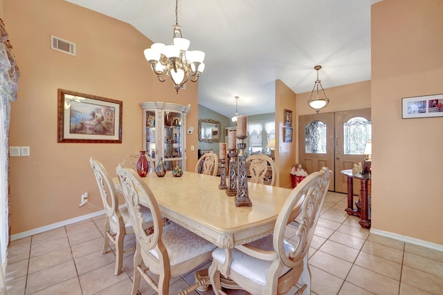 dining space featuring lofted ceiling, light tile patterned floors, and an inviting chandelier