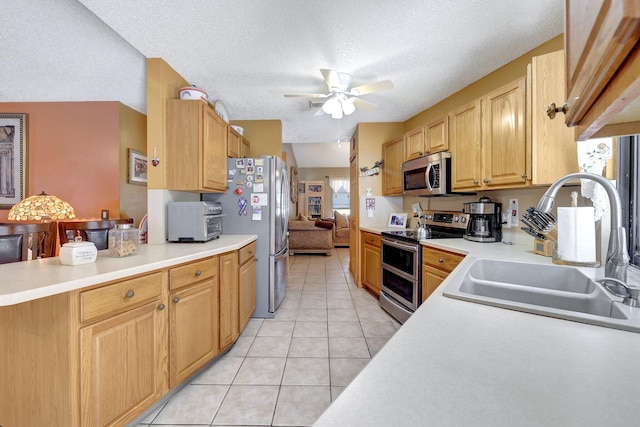 kitchen featuring sink, light tile patterned floors, ceiling fan, stainless steel appliances, and a textured ceiling