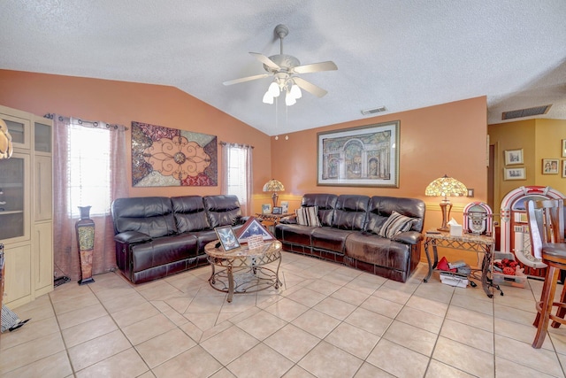 living room featuring light tile patterned flooring, ceiling fan, vaulted ceiling, and a textured ceiling