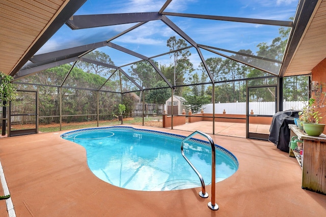 view of swimming pool with area for grilling, a storage shed, a patio area, and glass enclosure