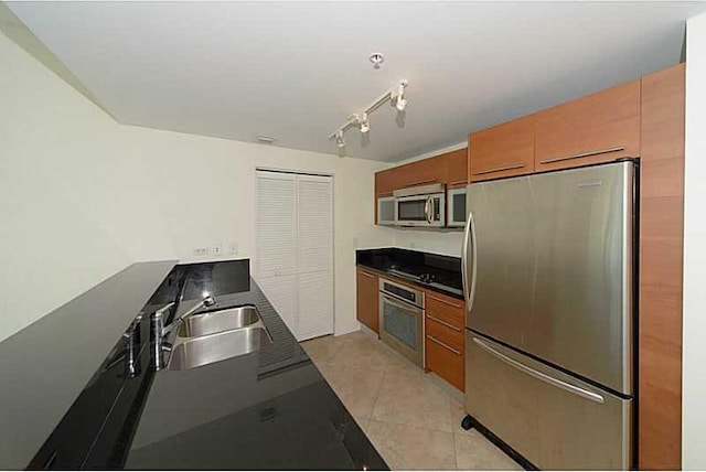 kitchen with sink, light tile patterned floors, stainless steel appliances, and rail lighting