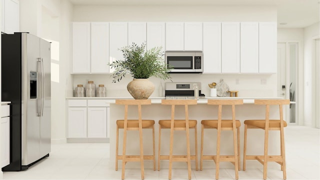 kitchen with a kitchen breakfast bar, white cabinetry, a kitchen island with sink, and appliances with stainless steel finishes