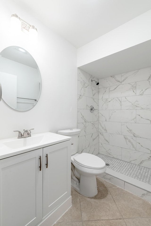 bathroom featuring tile patterned floors, vanity, toilet, and tiled shower