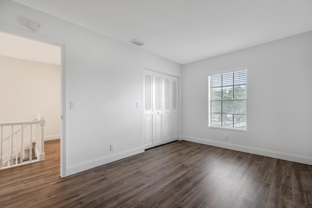 unfurnished bedroom with dark hardwood / wood-style flooring, a closet, and a textured ceiling