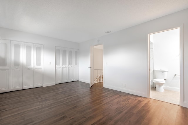 18520 SE Wood Haven Ln Unit I, Jupiter, FL 33469 - unfurnished bedroom with two closets, dark wood-type flooring, baseboards, and ensuite bathroom