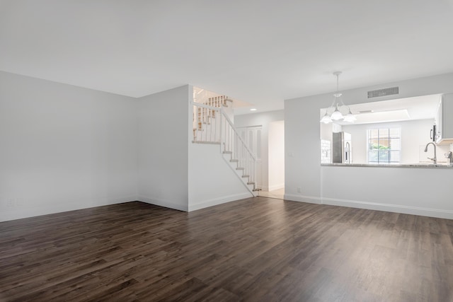 unfurnished living room with sink, dark wood-type flooring, and a chandelier