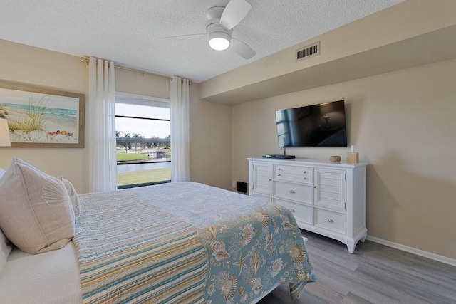 bedroom with ceiling fan, light hardwood / wood-style floors, and a textured ceiling