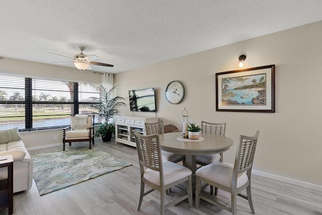 dining area featuring baseboards, a textured ceiling, wood finished floors, and a ceiling fan