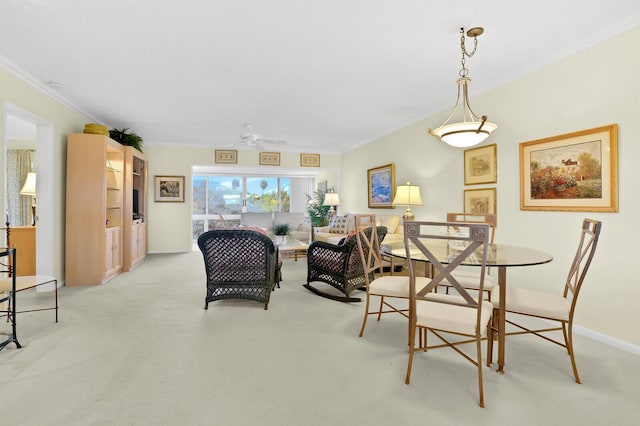 carpeted dining area with crown molding and ceiling fan