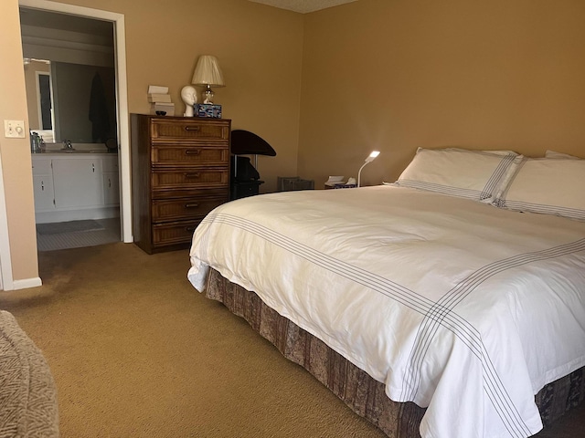 bedroom featuring sink, light carpet, and ensuite bath