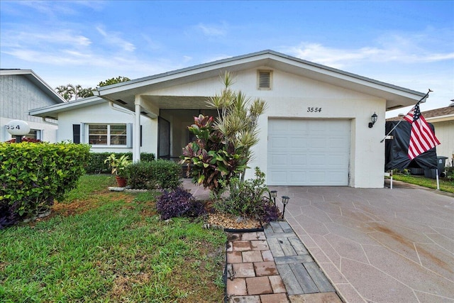 ranch-style home featuring driveway, an attached garage, and stucco siding