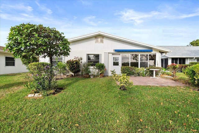 back of property with a patio area, a yard, and stucco siding