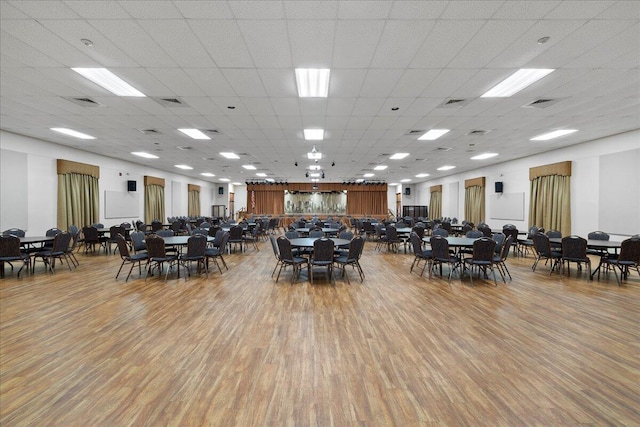 dining space with light wood finished floors, visible vents, and a drop ceiling