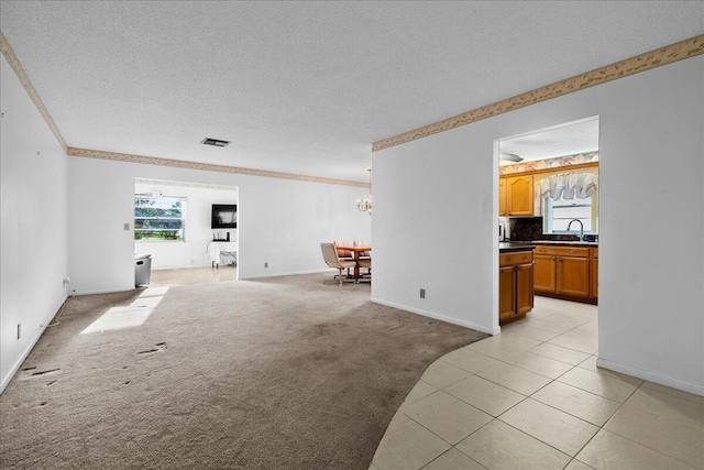 living room with light colored carpet, a healthy amount of sunlight, visible vents, and a textured ceiling