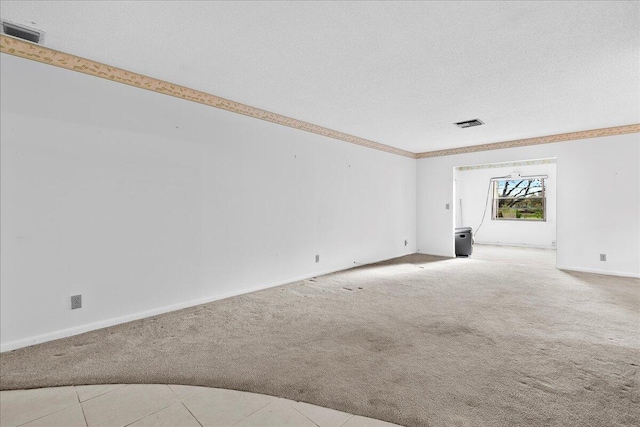 spare room featuring a textured ceiling, visible vents, and light colored carpet