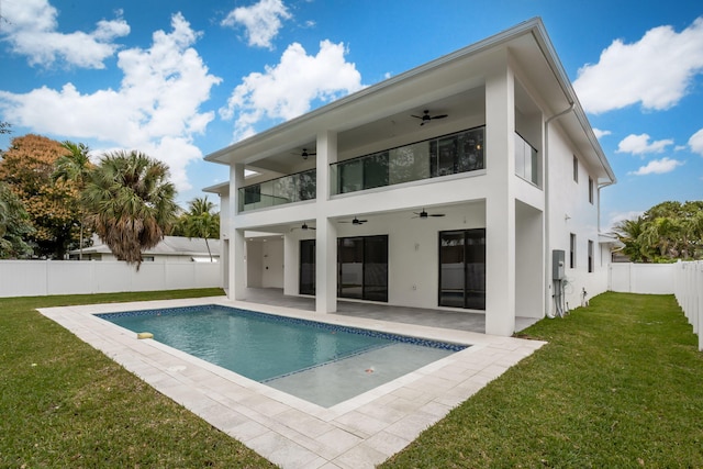 back of house featuring ceiling fan, a patio area, a balcony, a yard, and a fenced in pool