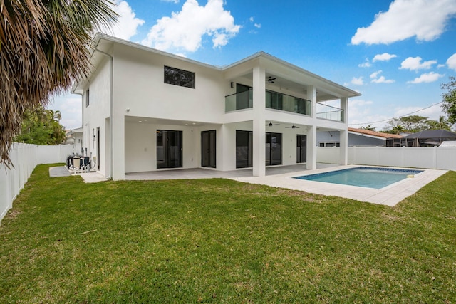 back of property featuring a lawn, a fenced in pool, a balcony, and a patio