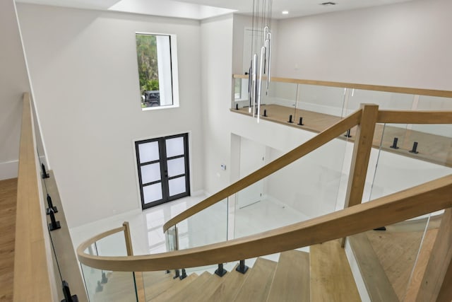 stairs with hardwood / wood-style floors and french doors