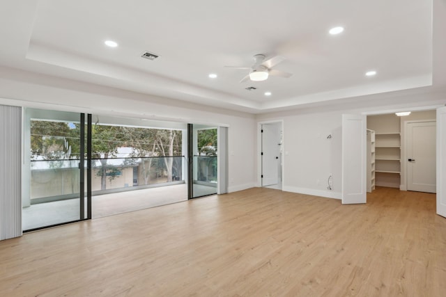 interior space featuring ceiling fan, a tray ceiling, and light hardwood / wood-style flooring