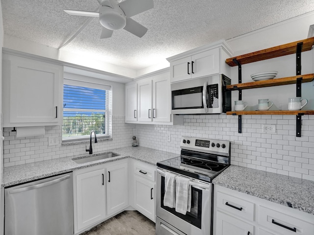 kitchen featuring sink, white cabinetry, light stone counters, ceiling fan, and appliances with stainless steel finishes