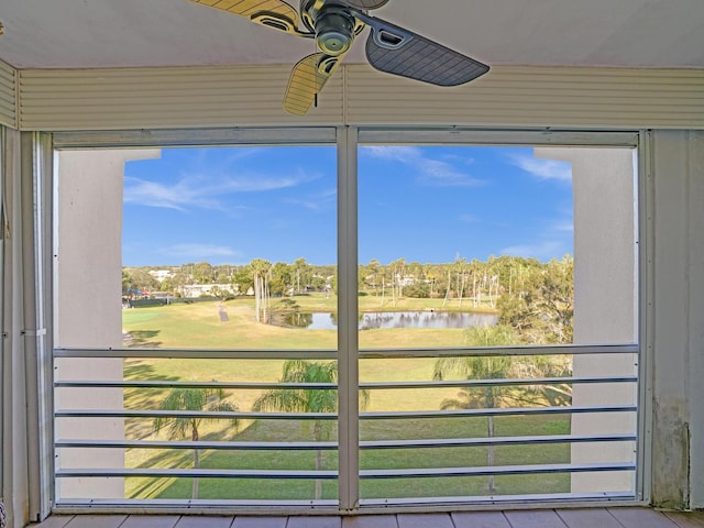 interior space with ceiling fan, a water view, and tile patterned floors