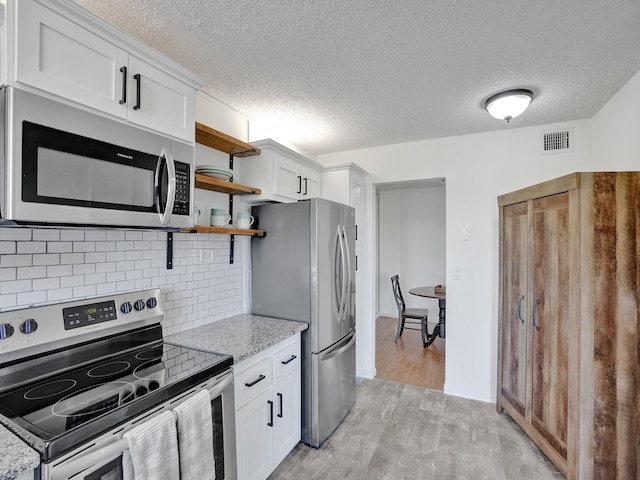 kitchen featuring light stone countertops, white cabinets, tasteful backsplash, and appliances with stainless steel finishes