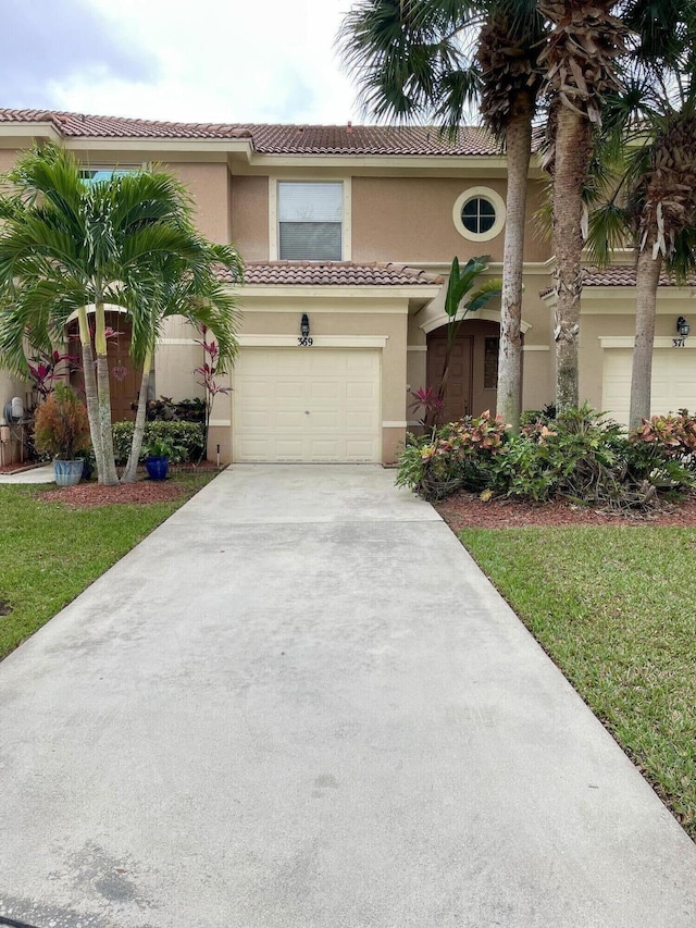 mediterranean / spanish home with a garage, driveway, a tiled roof, and stucco siding