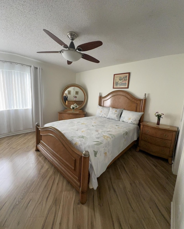 bedroom with a textured ceiling, ceiling fan, and hardwood / wood-style flooring