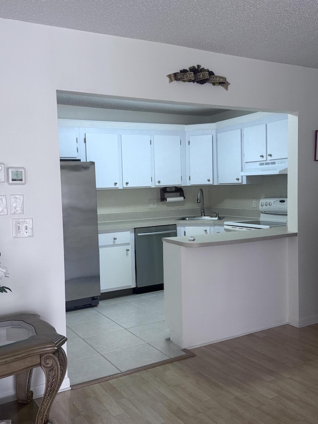 kitchen featuring white cabinetry, stainless steel appliances, light wood-type flooring, a textured ceiling, and sink