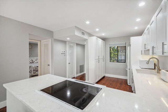 kitchen featuring kitchen peninsula, black electric stovetop, sink, white cabinets, and dark hardwood / wood-style floors