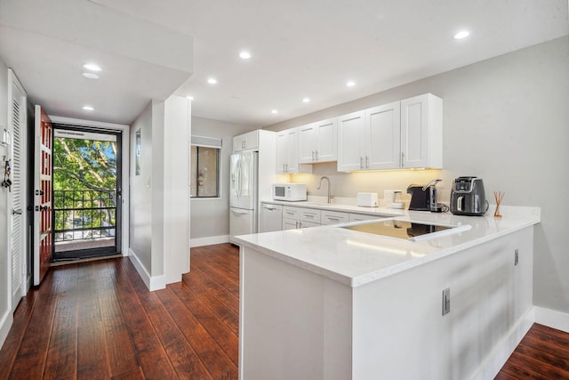 kitchen featuring kitchen peninsula, light stone counters, white appliances, white cabinets, and dark hardwood / wood-style floors