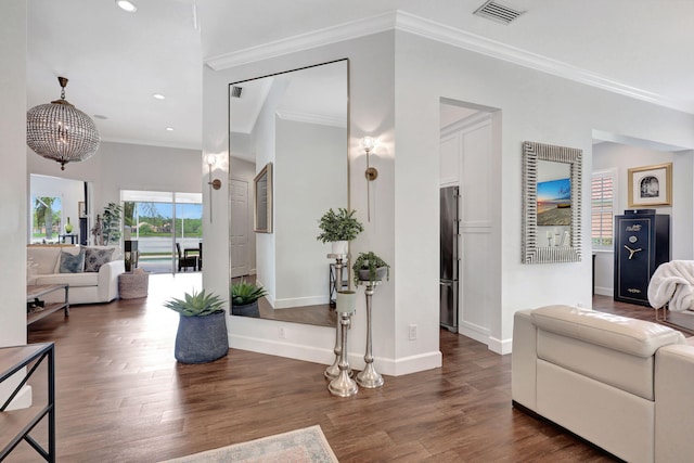 living room featuring dark wood-type flooring, ornamental molding, and a notable chandelier