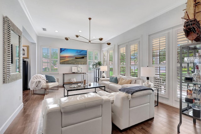 living room with dark wood-type flooring, crown molding, and an inviting chandelier