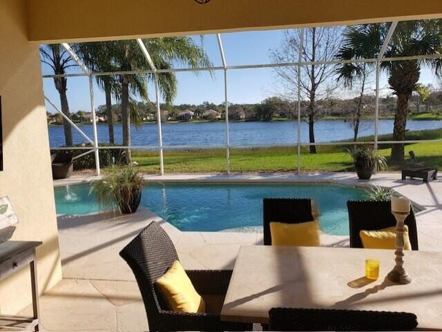 view of swimming pool featuring a patio, a water view, and glass enclosure